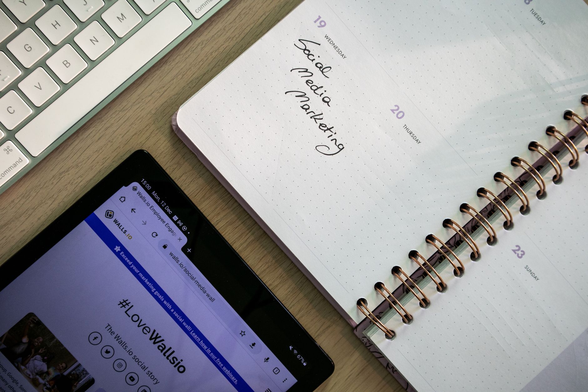 Notizbuch mit handschriftlichem Eintrag Social Media Marketing neben Tablet und Tastatur
