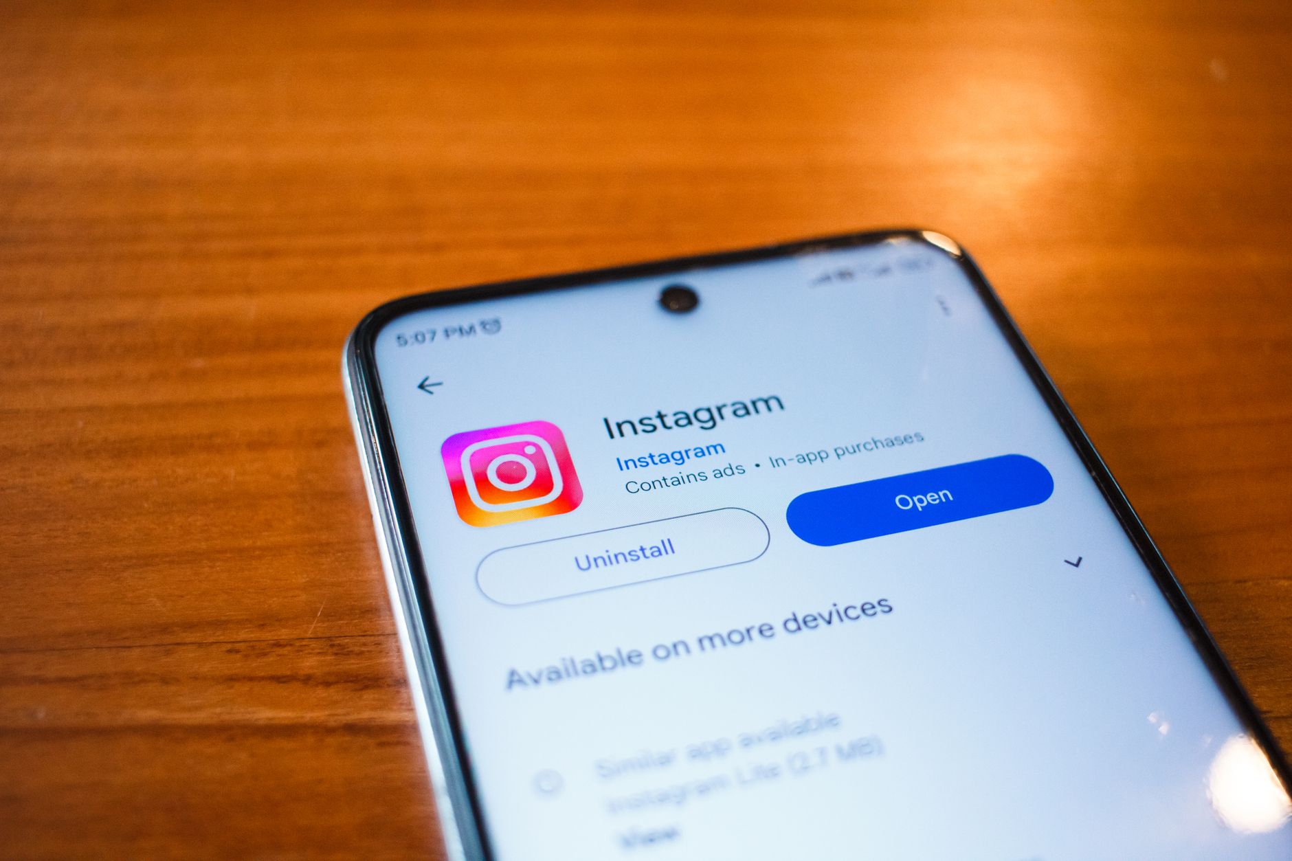 Smartphone mit geöffneter Instagram-Seite im App-Store auf einem Holztisch