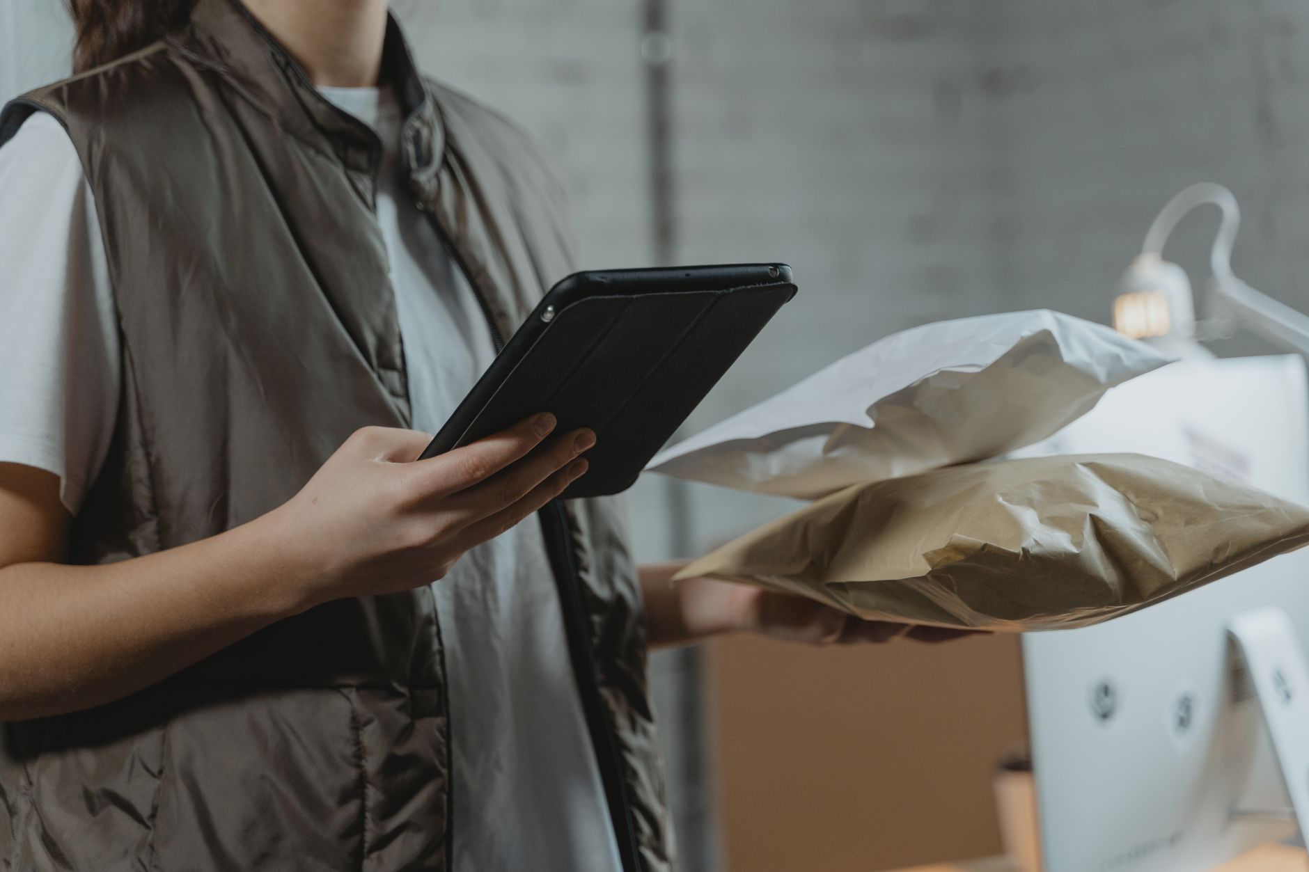Mitarbeiterin prüft an einem Tablet Versandpakete im Lager