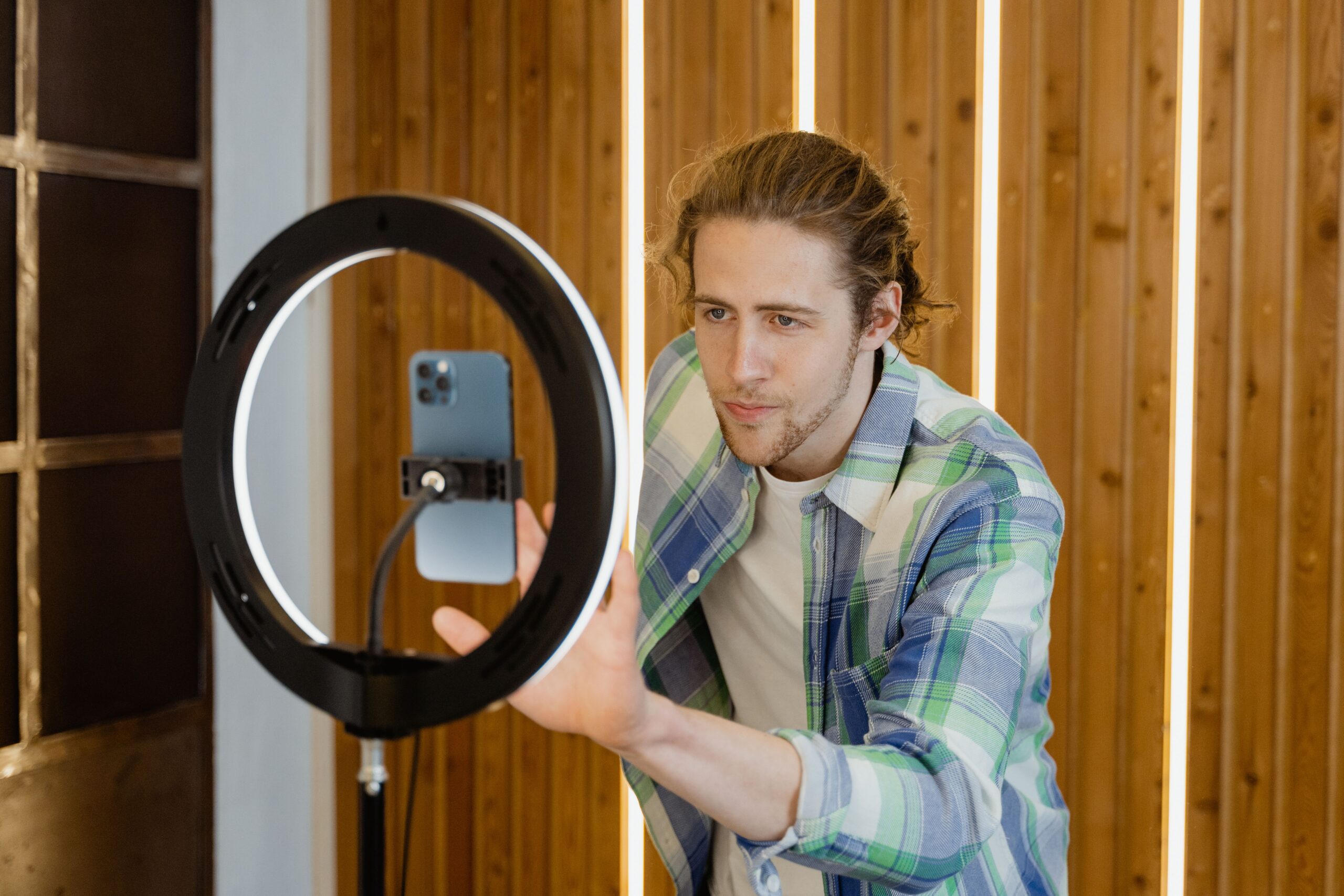 Ein Mann richtet ein Smartphone auf einem Stativ mit Ringlicht für eine Videoaufnahme ein